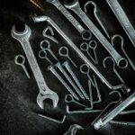 Collection of metal tools including wrenches and screws on a textured surface, ideal for DIY and repair themes.
